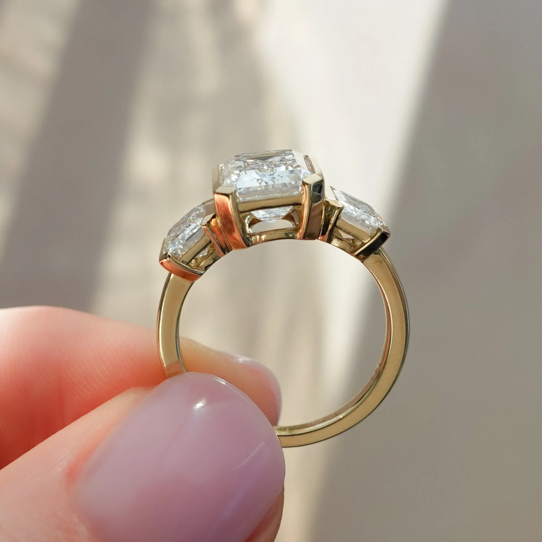 Half Bezel Triad Engagement Ring With Emerald Cut Diamonds